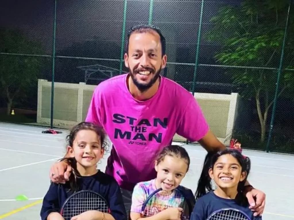 An AK Tennis coach with a junior group on a floodlit court in Dubai