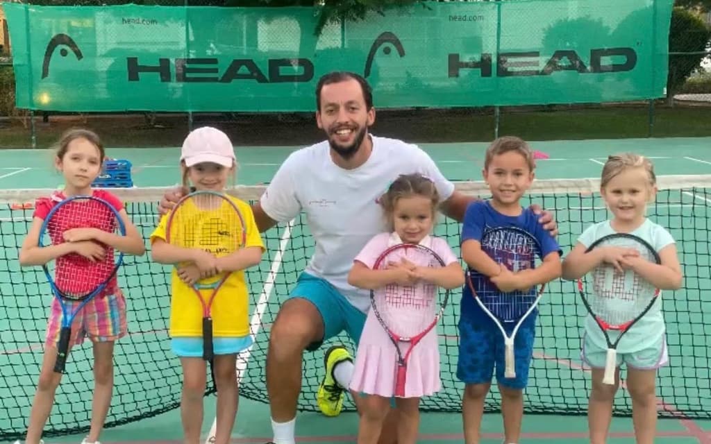 An AK Tennis coach with a junior group at the net in Dubai